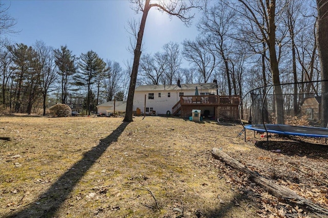 view of yard featuring a trampoline, a deck, and stairs
