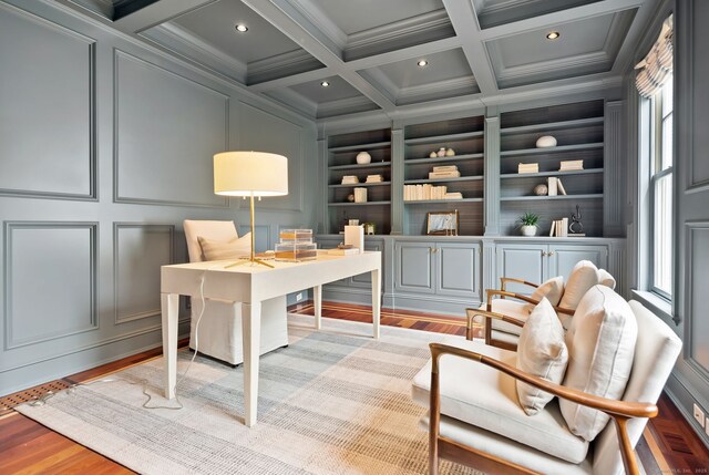 office space with built in shelves, healthy amount of natural light, a decorative wall, wood finished floors, and crown molding