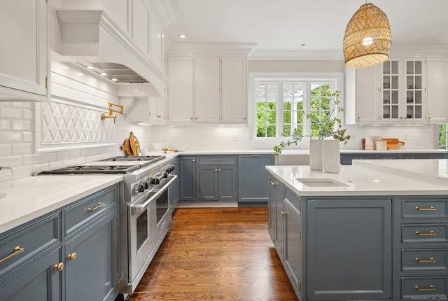 kitchen with range with two ovens, white cabinetry, premium range hood, light countertops, and crown molding
