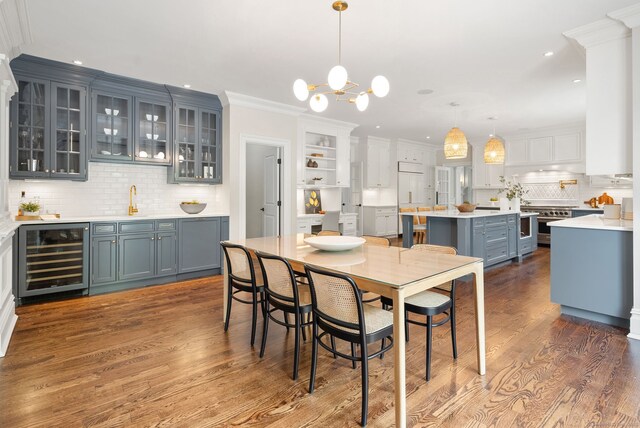 dining space with beverage cooler, dark wood-style flooring, wet bar, a chandelier, and recessed lighting