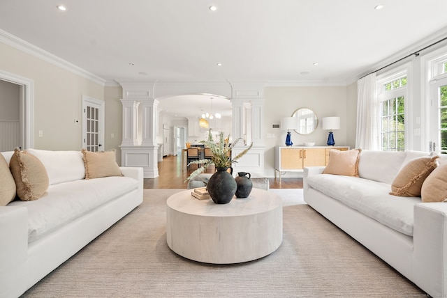 living area with decorative columns, arched walkways, recessed lighting, ornamental molding, and a chandelier