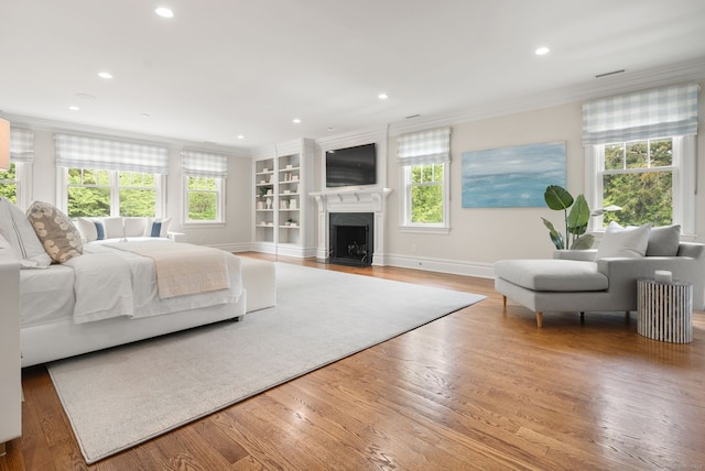 bedroom with crown molding, recessed lighting, wood finished floors, baseboards, and a fireplace