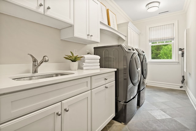 laundry area with washing machine and dryer, cabinet space, ornamental molding, light tile patterned floors, and baseboards