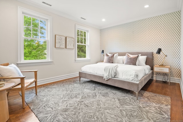 bedroom with crown molding, baseboards, wood finished floors, multiple windows, and wallpapered walls