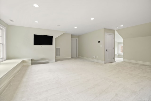 unfurnished living room with recessed lighting, light colored carpet, vaulted ceiling, baseboards, and healthy amount of natural light