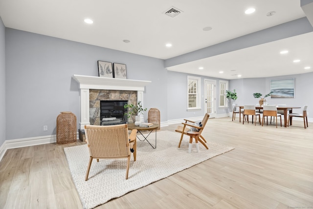living area with baseboards, light wood-type flooring, a fireplace, and recessed lighting