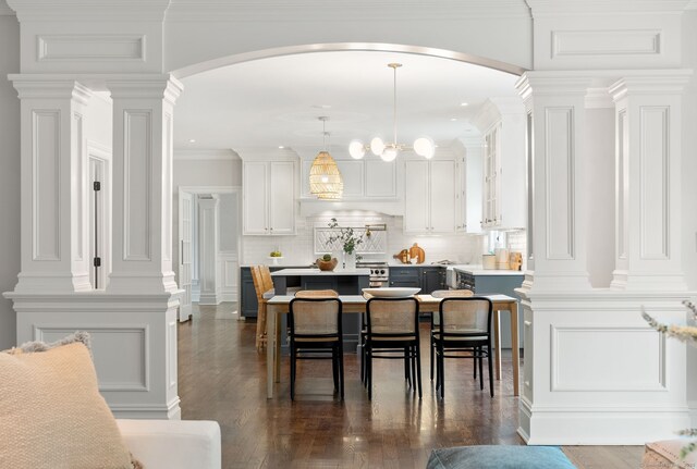 dining space featuring arched walkways, a decorative wall, dark wood-type flooring, and recessed lighting