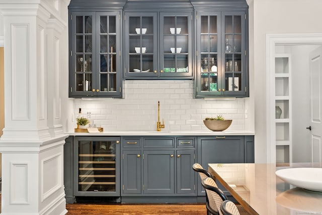 indoor wet bar featuring beverage cooler and backsplash