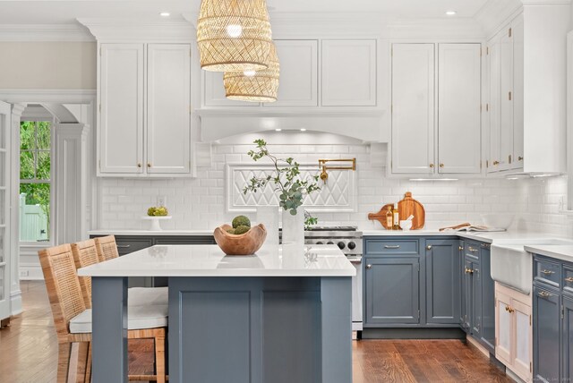 kitchen featuring light countertops, dark wood-style flooring, a kitchen bar, decorative backsplash, and ornamental molding