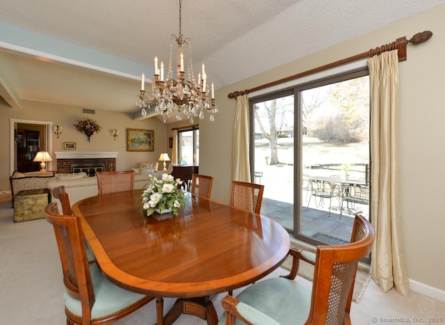dining room with visible vents, a fireplace, a textured ceiling, a notable chandelier, and light colored carpet