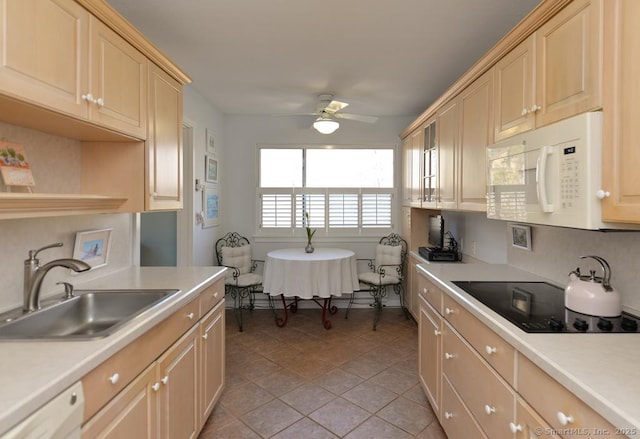 kitchen with a sink, white appliances, a ceiling fan, and light countertops