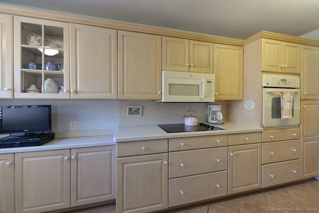 kitchen featuring glass insert cabinets, light brown cabinetry, light countertops, light tile patterned floors, and white appliances