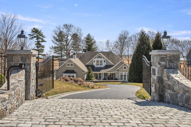 view of front of property featuring a gate, fence, and curved driveway