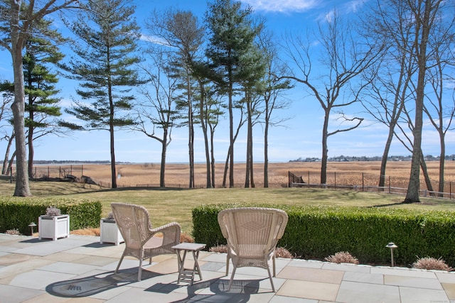 view of patio with fence and a rural view
