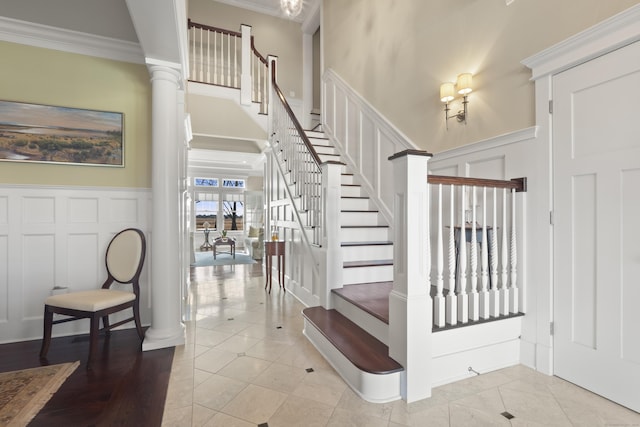 staircase with a decorative wall, ornamental molding, tile patterned flooring, and decorative columns