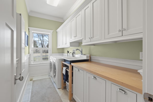 laundry area featuring washing machine and clothes dryer, a sink, cabinet space, crown molding, and light tile patterned floors