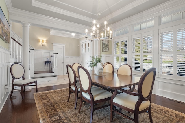 dining room with dark wood-style flooring, a chandelier, ornamental molding, and a decorative wall