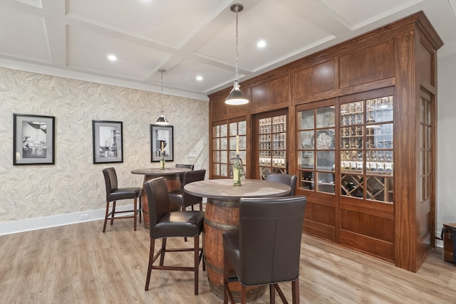 bar featuring baseboards, hanging light fixtures, coffered ceiling, and light wood-type flooring