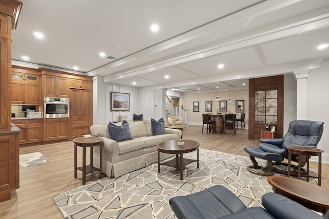 living area featuring recessed lighting, stairs, light wood-style floors, and decorative columns