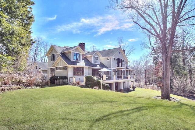 view of front of home featuring a front lawn, a chimney, a shingled roof, and a wooden deck