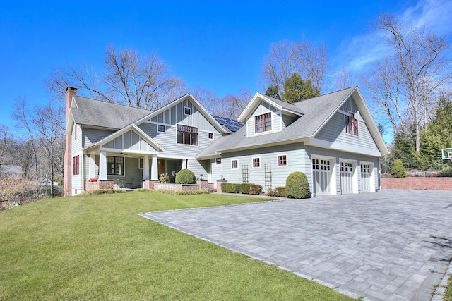 view of front of property with a front yard, covered porch, roof with shingles, a chimney, and board and batten siding