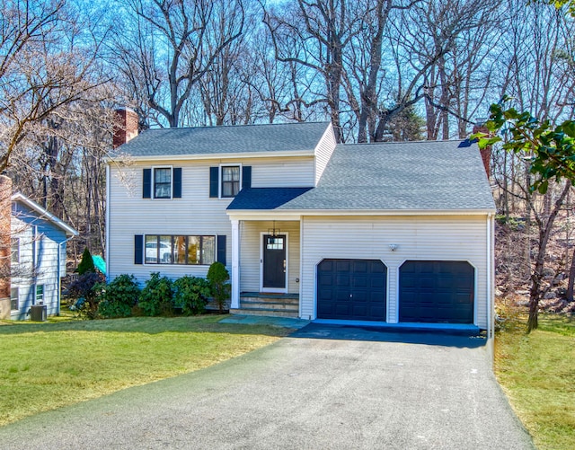 view of front of home with a shingled roof, a front lawn, aphalt driveway, cooling unit, and an attached garage