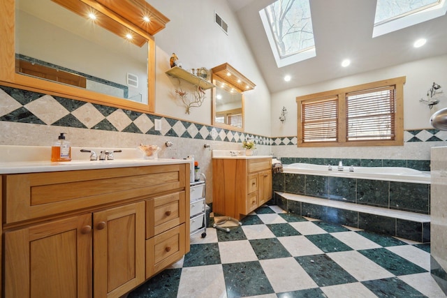 16 Fullmar Ln, Norwalk, CT 06850 - bathroom with a skylight, a bath, two vanities, tile walls, and plenty of natural light