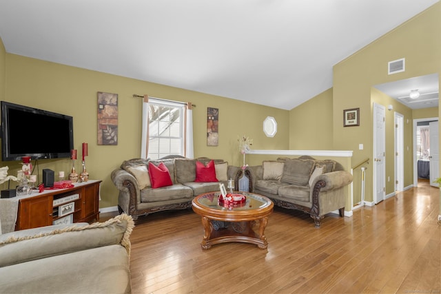 living area featuring lofted ceiling, hardwood / wood-style flooring, baseboards, and visible vents