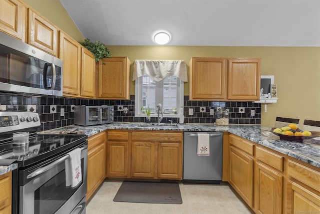 kitchen with a toaster, decorative backsplash, stone countertops, stainless steel appliances, and a sink