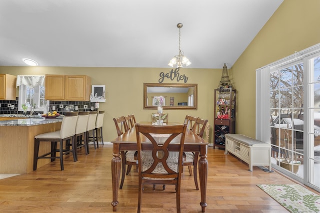 dining space featuring baseboards, lofted ceiling, and light wood-style flooring