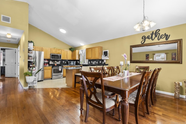 dining space featuring light wood-type flooring, visible vents, high vaulted ceiling, an inviting chandelier, and baseboards