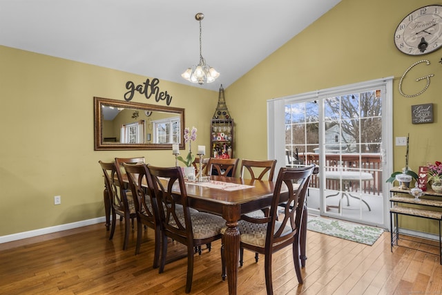 dining room featuring baseboards, an inviting chandelier, hardwood / wood-style floors, and vaulted ceiling