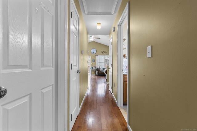 hallway with baseboards, attic access, hardwood / wood-style floors, and vaulted ceiling