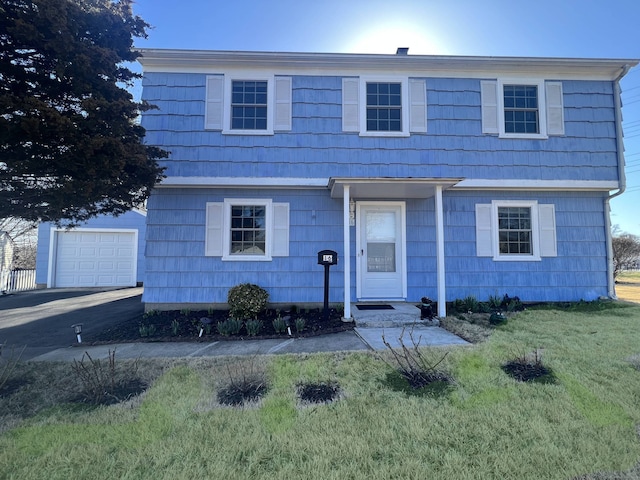 colonial home with a garage, aphalt driveway, and a front lawn