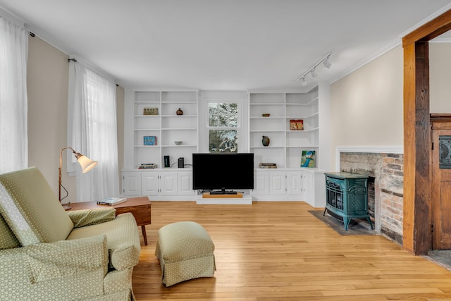 387 N River St, Guilford, CT 06437 - living area with a wood stove, built in features, light wood-style flooring, rail lighting, and ornamental molding