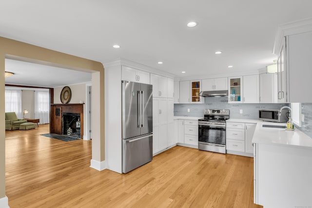 387 N River St, Guilford, CT 06437 - kitchen with appliances with stainless steel finishes, light countertops, under cabinet range hood, light wood finished floors, and backsplash