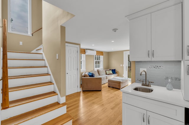 387 N River St, Guilford, CT 06437 - kitchen with a sink, a wall mounted air conditioner, tasteful backsplash, light countertops, and light wood finished floors