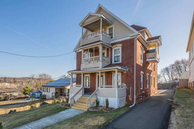 45 Willis St, Bristol, CT 06010 - view of front of property with a front yard, a balcony, covered porch, aphalt driveway, and brick siding