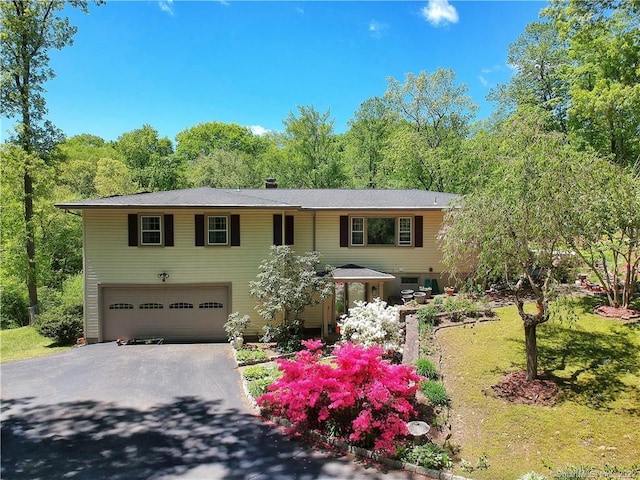 view of front of house featuring a chimney, aphalt driveway, and an attached garage
