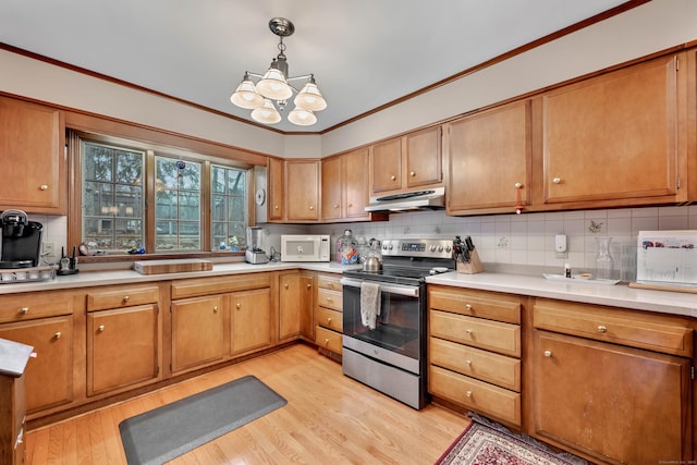 kitchen featuring tasteful backsplash, light wood-style flooring, under cabinet range hood, and stainless steel electric range