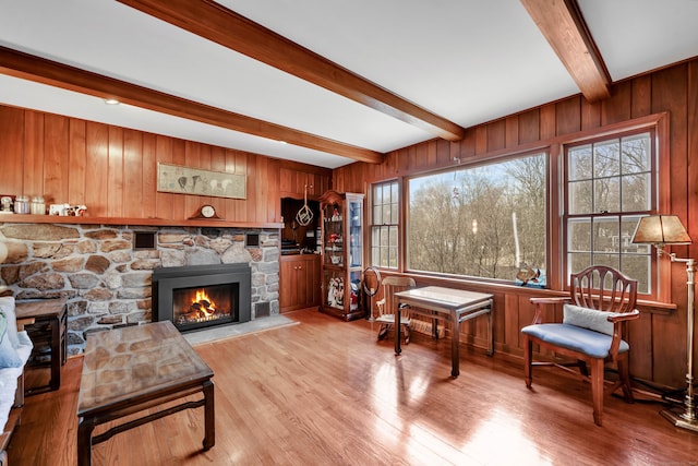 living room featuring light wood finished floors, a fireplace, and wooden walls
