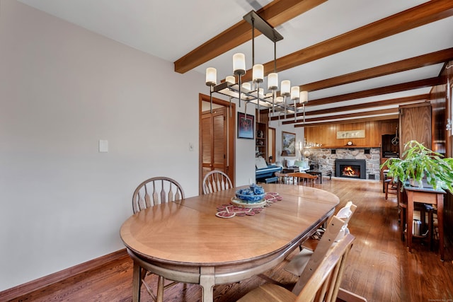 dining space with a fireplace, beam ceiling, an inviting chandelier, and hardwood / wood-style flooring
