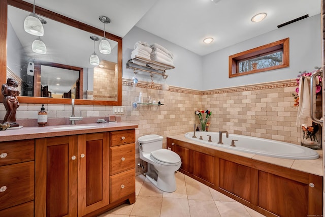 bathroom featuring toilet, vanity, tile patterned flooring, a bath, and tile walls