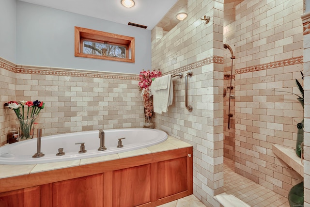 bathroom with a shower stall, tile walls, visible vents, and a bath