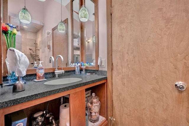 bathroom featuring tiled shower and vanity