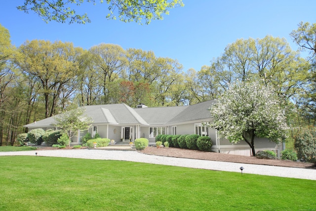 ranch-style house featuring a front lawn and a chimney