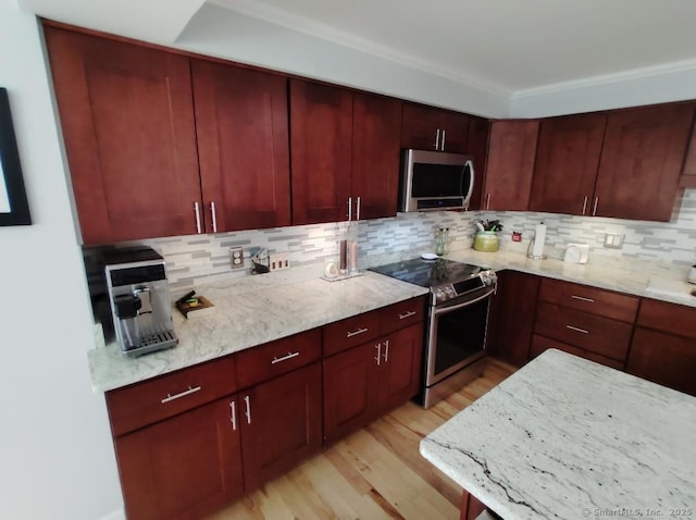 kitchen with light wood-style flooring, dark brown cabinets, light stone counters, stainless steel appliances, and decorative backsplash