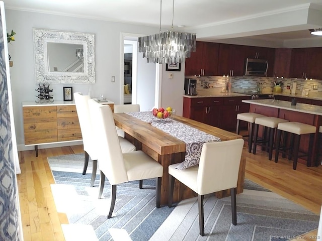 dining space featuring an inviting chandelier, light wood-style floors, and ornamental molding