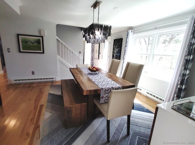 dining room featuring stairway, a notable chandelier, wood finished floors, and baseboard heating