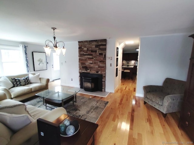 living room featuring a wood stove, an inviting chandelier, and wood finished floors